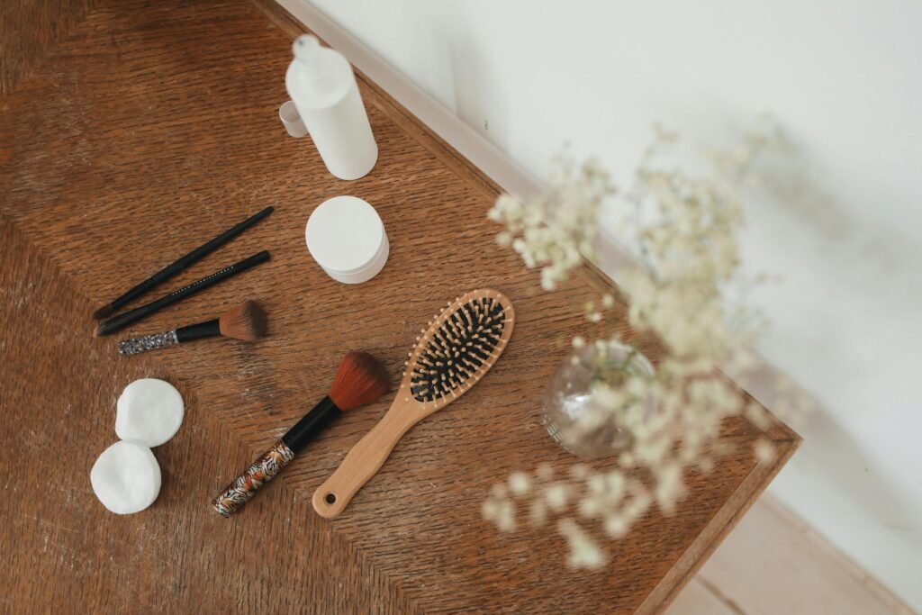 Top view of beauty tools and accessories on a wooden table with flowers.