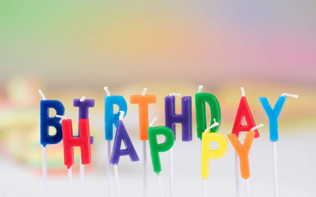 Vibrant birthday candle letters spelling 'Happy Birthday' with a colorful blurred background. Perfect for celebration visuals.
