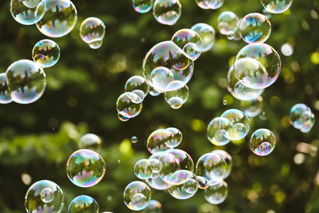 A vibrant and playful scene of colorful soap bubbles floating against a lush green background.