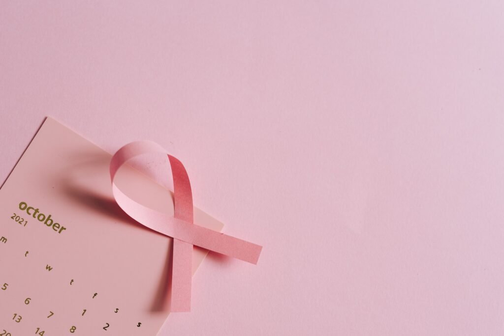 Breast cancer awareness concept with a pink ribbon on a pink October calendar.